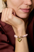 Pink rope bracelet with gold heart charm and gold rings.