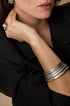 Close-up of a woman's arm wearing a stack of five brushed silver bangles.