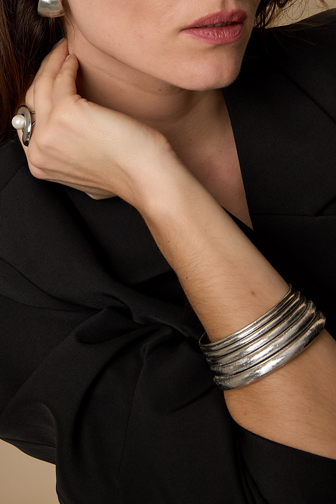 Close-up of a woman's arm wearing a stack of five brushed silver bangles.