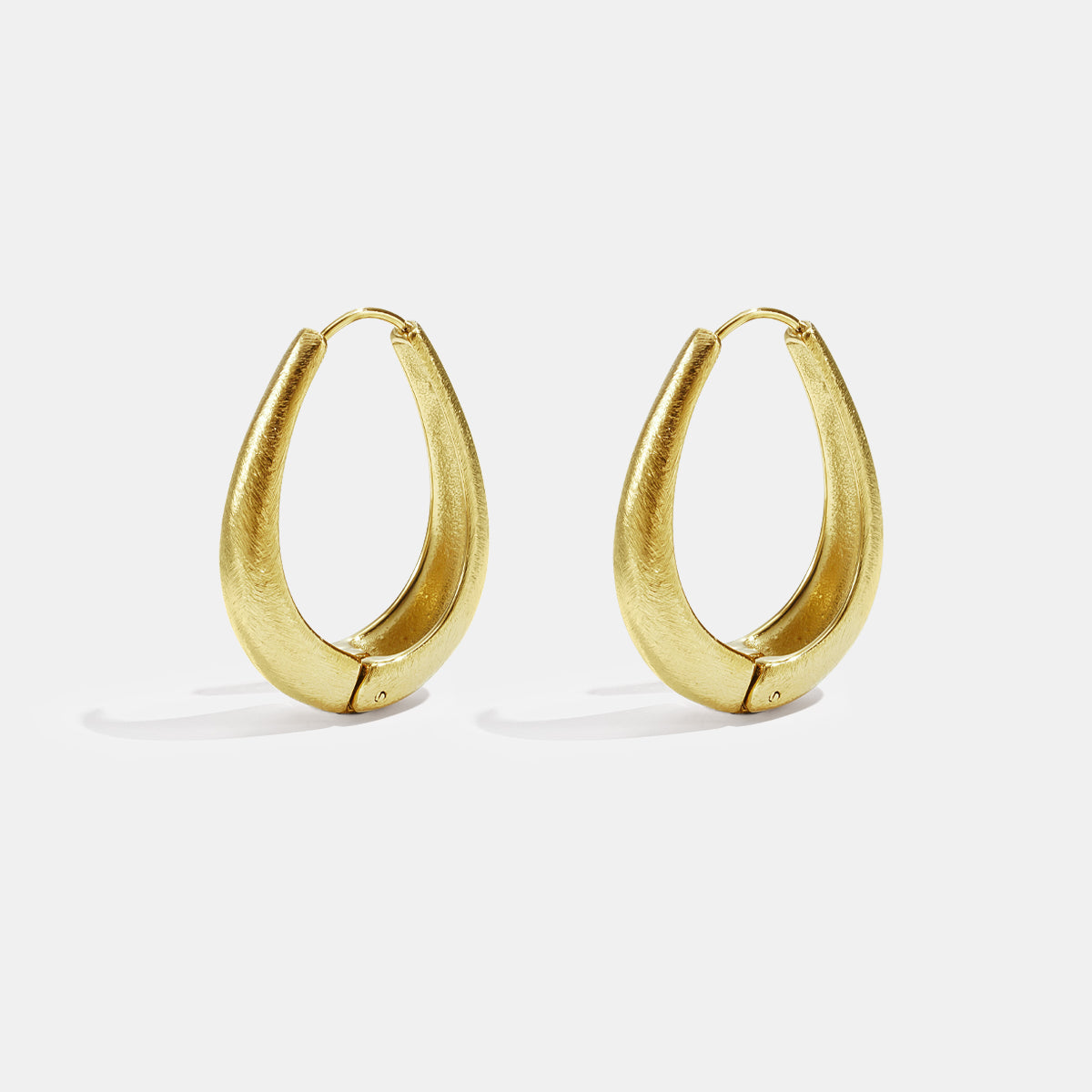 Gold irregular oval hoop earrings with a brushed finish.