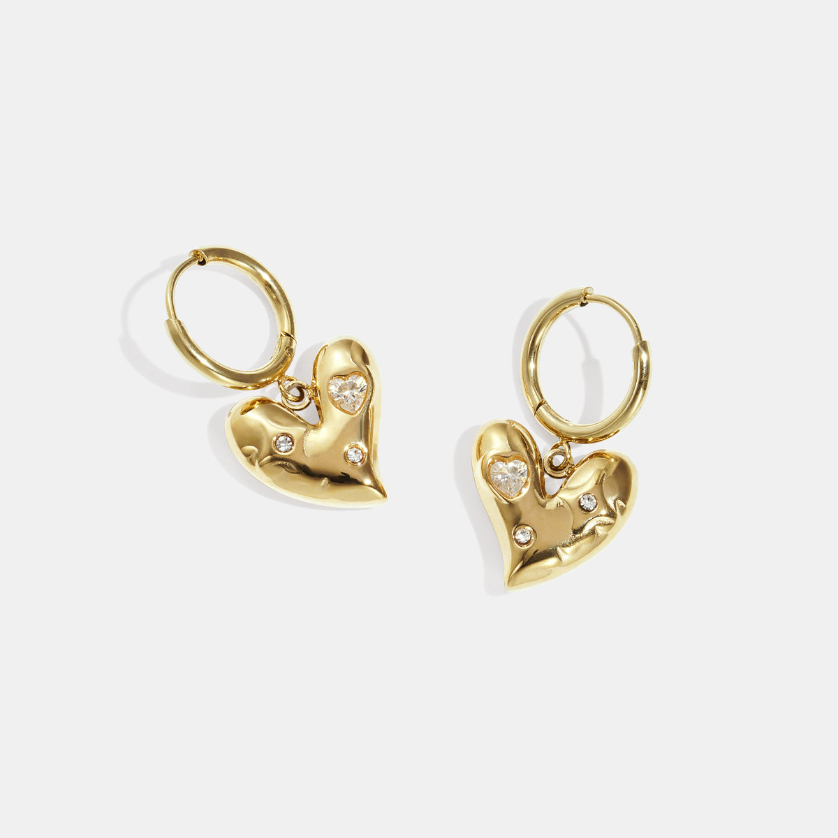 Gold heart-shaped drop earrings with small rhinestones and a gold hoop.