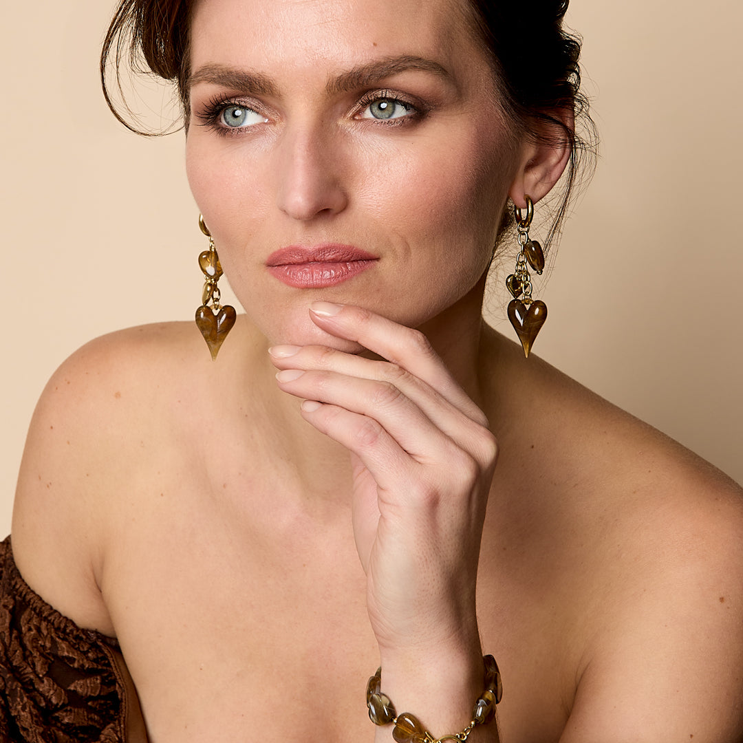 Beaded bracelet with brown heart charms and gold accents, worn on a woman's wrist.