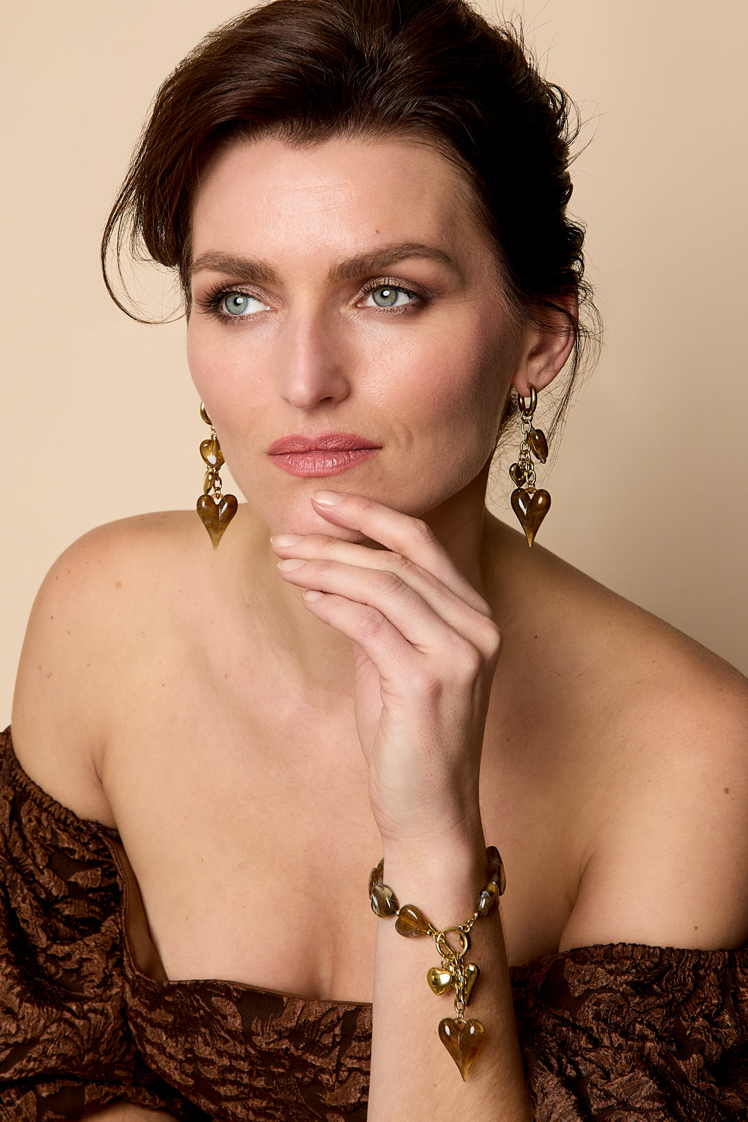 Beaded bracelet with brown heart charms and gold accents, worn on a woman's wrist.